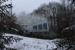 Besucherpavillon des Radio-Observatoriums Effelsberg im Winter. Das 100-m-Radioteleskop spiegelt sich in der Panoramascheibe des Pavillons.
