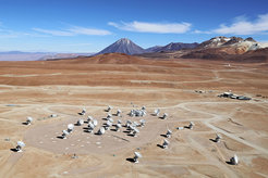 Astronomy in the desert: An aerial photograph of the Chajnantor Plateau with the antennas of the ALMA Observatory situated more than 5,000 m above sea level in the Chilean Andes. The peaks of Juriques, Cerro Toco, and Cerro Chajnantor (from left) are visible on the horizon. The photograph was taken in December 2012, three months before the official opening of ALMA.