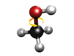 Schematic image of the methanol molecule. The black sphere represents the central carbon atom, the red one an oxygen atom and the grey spheres represent hydrogen atoms. The yellow arrow represents the internal rotation of the molecule, whose impediment causes a quantum tunnel effect.