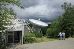Der Besucherpavillon des Radio-Observatoriums Effelsberg mit dem 100-m-Radioteleskop im Hintergrund. Dort finden in den Monaten April bis Oktober Vorträge für Besuchergruppen statt. Vom Pavillon aus führt ein kurzer Weg bis zu einem Aussichtspunkt unmittelbar vor dem großen Reflektor. Bitte beachten Sie, dass elektronische Geräte, vor allem Mobiltelefone, in Reichweite des Teleskops komplett ausgeschaltet oder in Flugmodus gebracht werden sollten, da die ausgesandte Strahlung („Elektrosmog“) die Messungen mit dem Radioteleskop empfindlich beeinträchtigt.