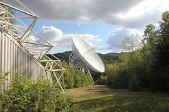 Ganz links: Besucherpavillon in direkter Sichtweite des Radioteleskops Effelsberg, Dort werden die Vorträge zum Astronomietag am 30. März 2019 stattfinden. Ein zickzackförmiger Zugangsweg führt bis zum Aussichtspunkt unmittelbar vor dem Teleskop selbst.