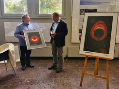 Abb. 1: Der Künstler Helge-W. Fechner bei der Übergabe eines Bildes von Sagittarius A* an Prof. Anton Zensus, Direktor am Max-Planck-Institut für Radioastronomie (MPIfR). Auf der rechten Bildseite die von Herrn Fechner gestaltete Collage „Das Schwarze Loch“, die am Dienstag, 26. Juli 2022 bei einer Zeremonie im Foyer des MPIfR an das Institut übergeben wurde.
